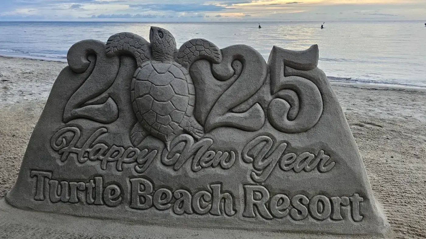 Roatan Fire Tours 27 Happy New Year 2025 sand sculpture with a sea turtle at Turtle Beach, West End, Roatan